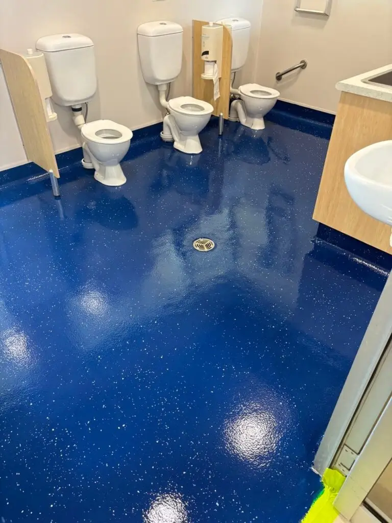 Epoxy flooring installed in a commercial bathroom with seamless waterproof finish